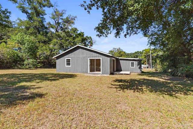 rear view of house with a storage unit and a yard