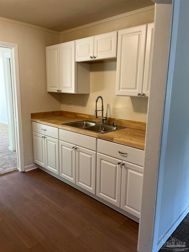 kitchen featuring white cabinetry, wood counters, and sink