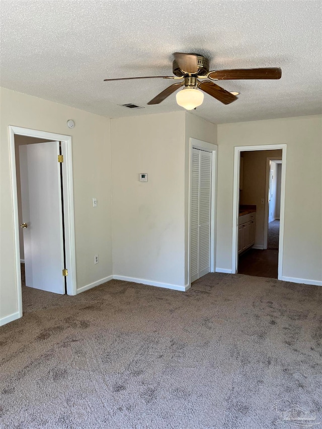 carpeted empty room featuring ceiling fan and a textured ceiling