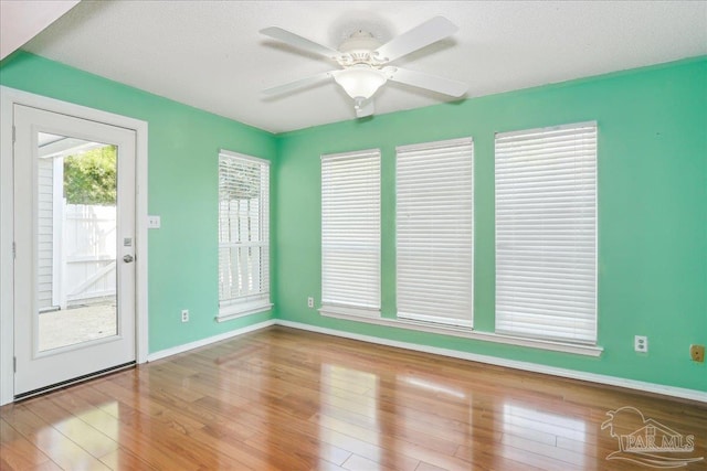 spare room with ceiling fan, baseboards, wood finished floors, and a textured ceiling
