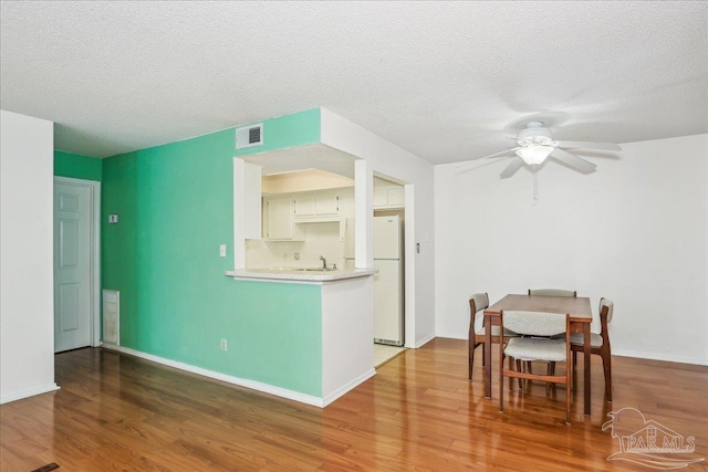 interior space featuring light countertops, freestanding refrigerator, wood finished floors, and visible vents