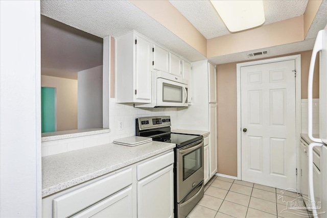 kitchen with white cabinets, stainless steel range with electric cooktop, visible vents, white microwave, and light tile patterned floors