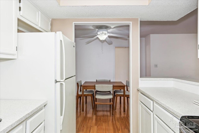 kitchen featuring light wood-type flooring, ceiling fan, range, white cabinets, and freestanding refrigerator
