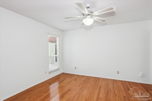 empty room with light wood-type flooring, a ceiling fan, and baseboards