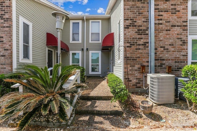 property entrance with brick siding and central air condition unit