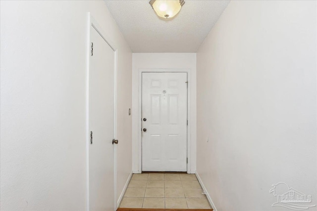 doorway with baseboards, light tile patterned flooring, and a textured ceiling