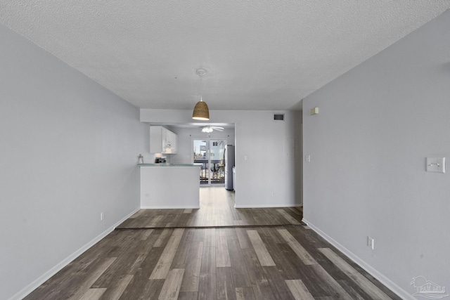 unfurnished living room with ceiling fan, dark hardwood / wood-style floors, and a textured ceiling