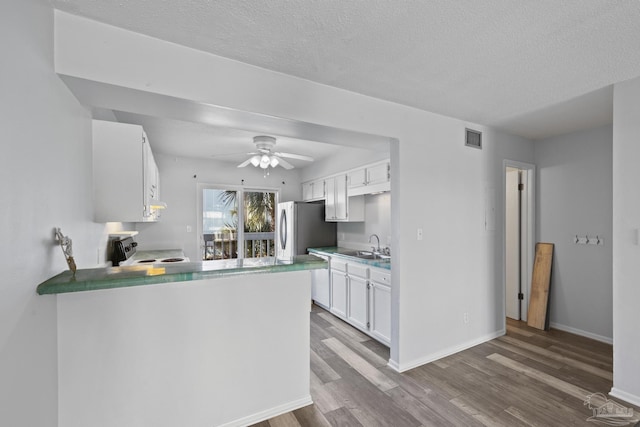 kitchen with dark wood-type flooring, white cabinets, sink, range with electric stovetop, and kitchen peninsula