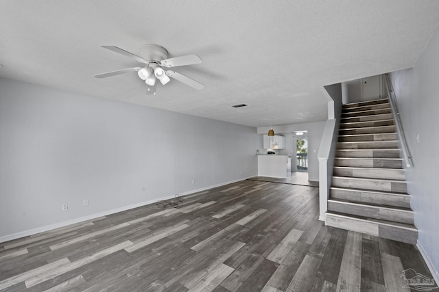 unfurnished living room with ceiling fan, dark wood-type flooring, and a textured ceiling