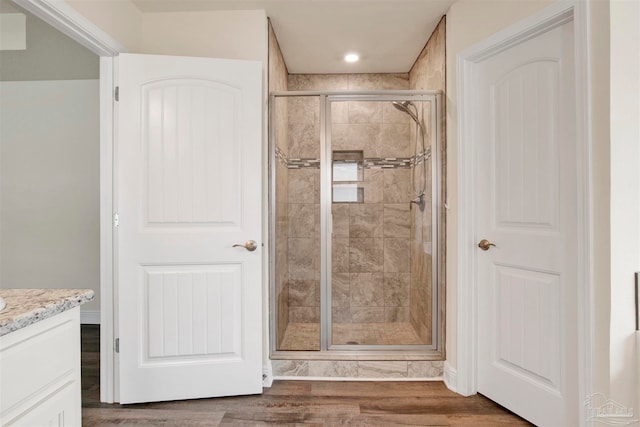 bathroom featuring vanity, a shower with shower door, and wood-type flooring