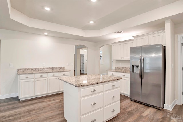 kitchen with white cabinetry, stainless steel fridge, a center island, and hardwood / wood-style floors