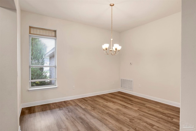 unfurnished room with wood-type flooring and an inviting chandelier