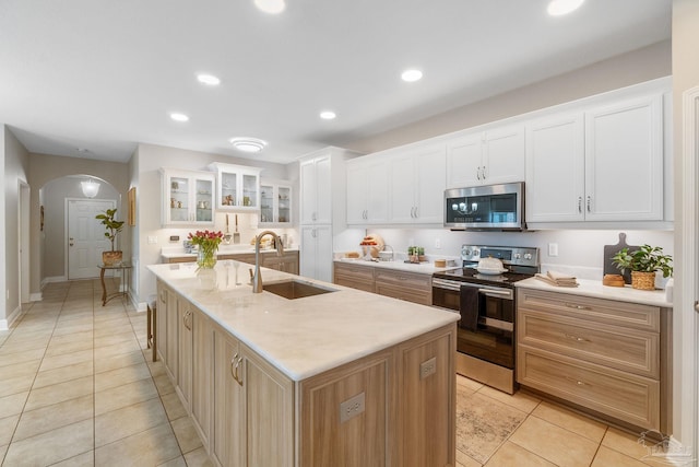 1777 Waterford Sound Blvd, Gulf Breeze, FL 32563 - kitchen featuring stainless steel appliances, a sink, arched walkways, a center island with sink, and light tile patterned floors
