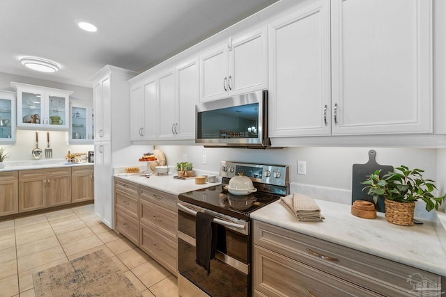 1777 Waterford Sound Blvd, Gulf Breeze, FL 32563 - kitchen featuring stainless steel appliances, light countertops, light tile patterned floors, glass insert cabinets, and white cabinetry