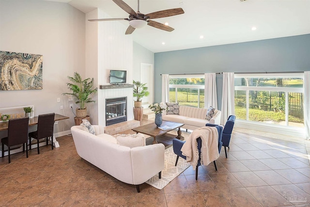 living room featuring ceiling fan, a fireplace, and high vaulted ceiling