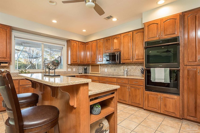 kitchen with black appliances, a center island, light tile patterned floors, and a breakfast bar area