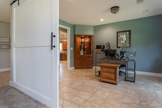 home office with a barn door and light tile patterned flooring