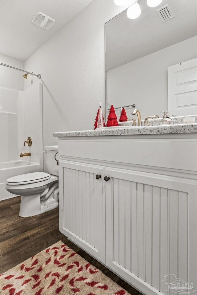 full bathroom featuring vanity, wood-type flooring,  shower combination, and toilet