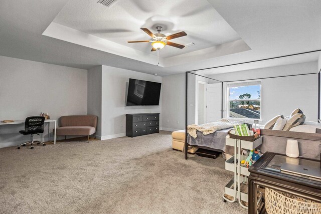 carpeted bedroom with ceiling fan and a raised ceiling