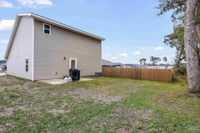 back of property with central AC unit, a patio, and a lawn