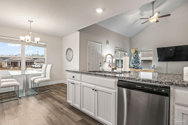 kitchen with dishwasher, dark stone counters, white cabinets, sink, and decorative light fixtures