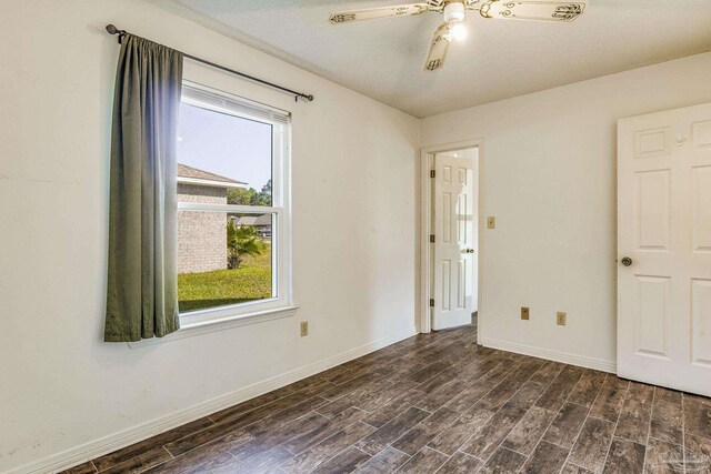 spare room featuring a textured ceiling, dark hardwood / wood-style floors, ceiling fan, and a healthy amount of sunlight