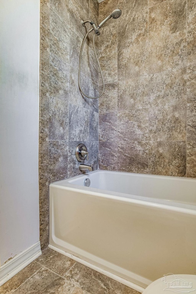 bathroom with tile patterned floors, tiled shower / bath combo, and toilet