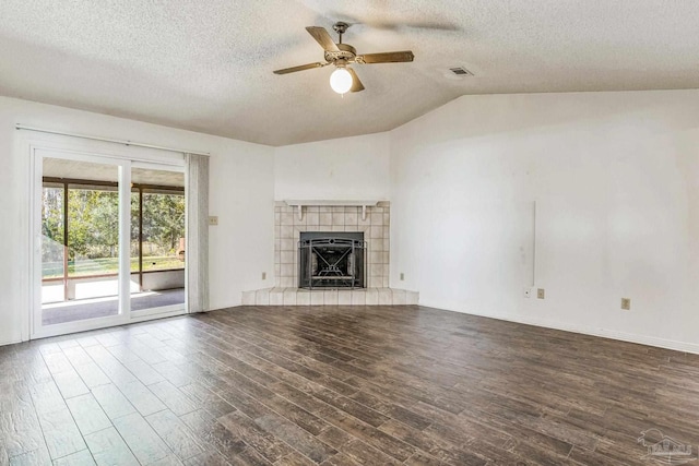 unfurnished living room featuring lofted ceiling, ceiling fan, a textured ceiling, wood-type flooring, and a tiled fireplace