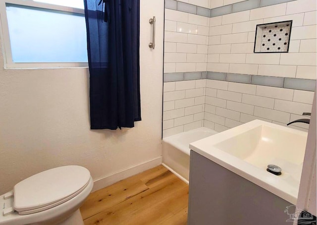 full bathroom featuring tiled shower / bath, hardwood / wood-style floors, vanity, and toilet