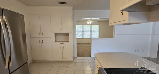 kitchen with white cabinets, ceiling fan, light tile patterned flooring, and stainless steel refrigerator