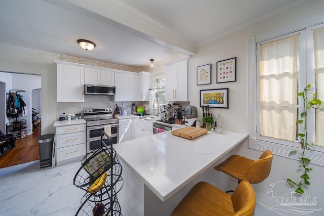 kitchen with tasteful backsplash, a breakfast bar area, stainless steel appliances, kitchen peninsula, and white cabinetry