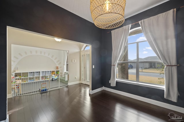 empty room with a water view, wood-type flooring, and an inviting chandelier