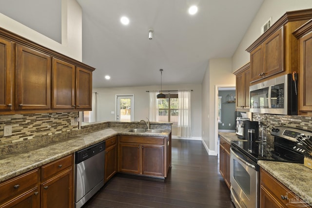kitchen featuring dark wood-type flooring, sink, vaulted ceiling, hanging light fixtures, and appliances with stainless steel finishes