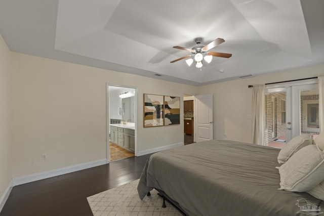 bedroom featuring ensuite bathroom, a tray ceiling, dark hardwood / wood-style flooring, and access to exterior