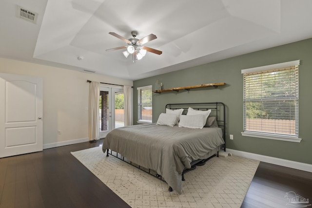 bedroom with access to exterior, dark hardwood / wood-style floors, a raised ceiling, and ceiling fan