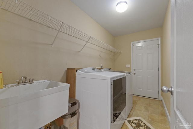 clothes washing area featuring sink, washer and clothes dryer, and light tile patterned flooring