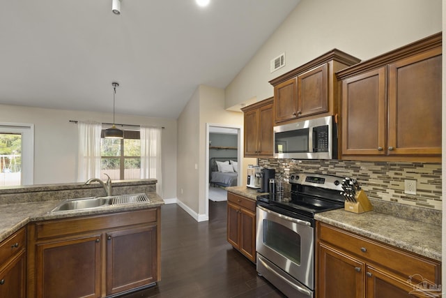 kitchen with vaulted ceiling, pendant lighting, sink, backsplash, and stainless steel appliances