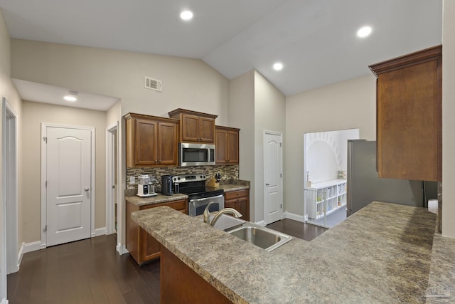 kitchen with appliances with stainless steel finishes, dark hardwood / wood-style floors, high vaulted ceiling, tasteful backsplash, and sink