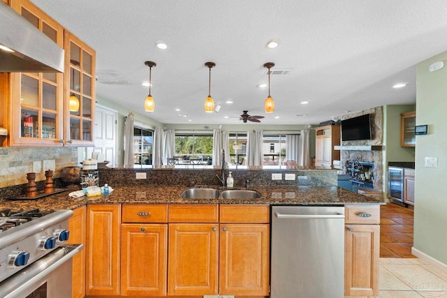 kitchen featuring sink, stainless steel appliances, beverage cooler, and dark stone counters