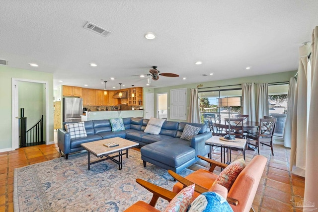 tiled living room with a textured ceiling and ceiling fan