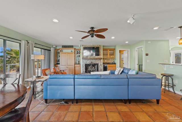 tiled living room with ceiling fan and a fireplace