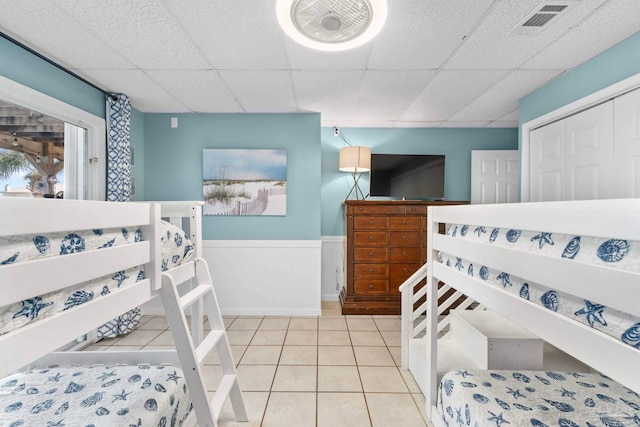 bedroom featuring a closet, light tile patterned flooring, and a drop ceiling