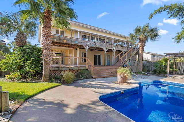 1113 Via Deluna Dr, Pensacola Beach, FL 32561 - rear view of house with a wooden deck, fence, a fenced in pool, a patio, and stairs