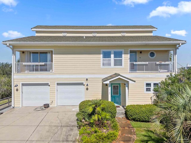 1113 Via Deluna Dr, Pensacola Beach, FL 32561 - view of front of house featuring fence, a balcony, concrete driveway, an attached garage, and a shingled roof