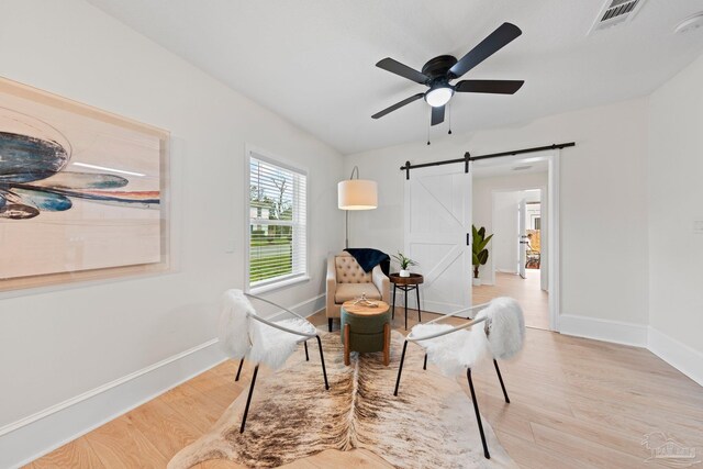 interior space with wood finished floors, visible vents, baseboards, and a barn door