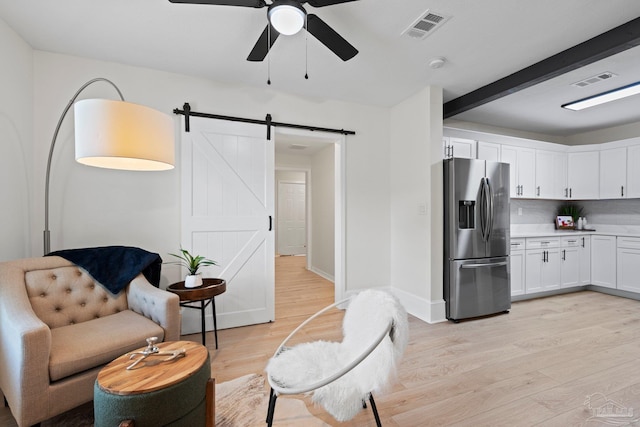 interior space with a barn door, light wood-type flooring, visible vents, and baseboards