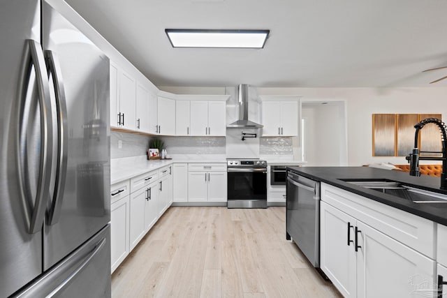 2512 N 8th Ave, Pensacola, FL 32503 - kitchen with appliances with stainless steel finishes, wall chimney exhaust hood, a sink, light wood-style floors, and tasteful backsplash
