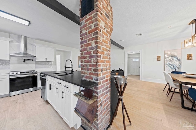 kitchen with stainless steel appliances, a sink, light wood-type flooring, decorative backsplash, and wall chimney exhaust hood