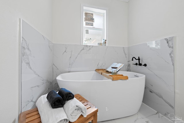 full bath with marble finish floor and a freestanding bath