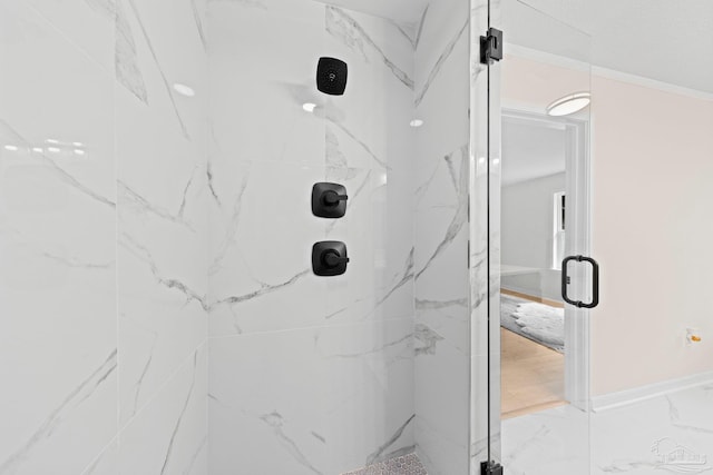 bathroom with marble finish floor, a marble finish shower, and baseboards